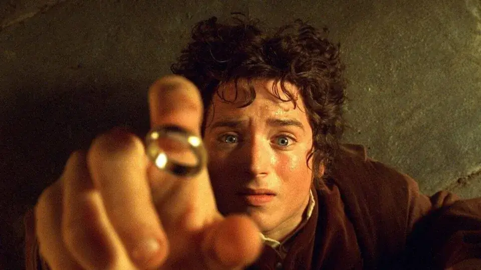 Frodo tenta pegar o anel em Senhor dos Anéis. Post para comemorar o dia do orgulho nerd.