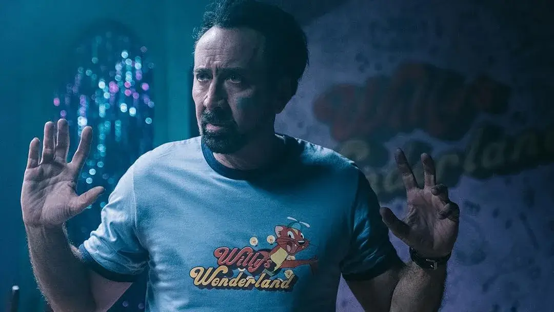 Nicolas Cage om os braços levantados no filme Willy's Wonderland. Post 5 Filmes Com Nicolas Cage que Você Ainda não Viu.