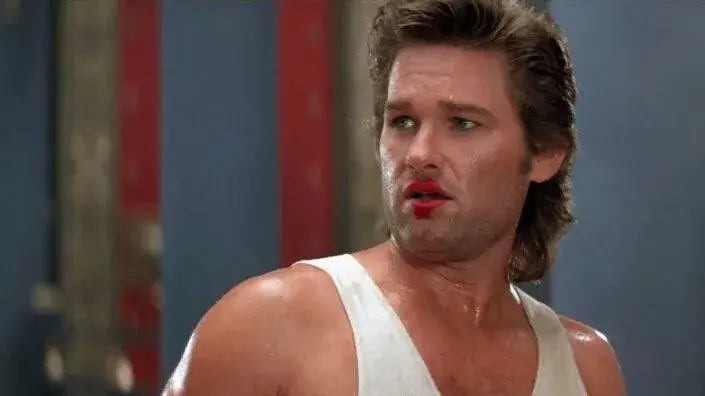 O protagonista Jack Burton aparece de regata branca e marca de batom na boca. Post Curiosidades e Bastidores: Os Aventureiros do Bairro Proibido.